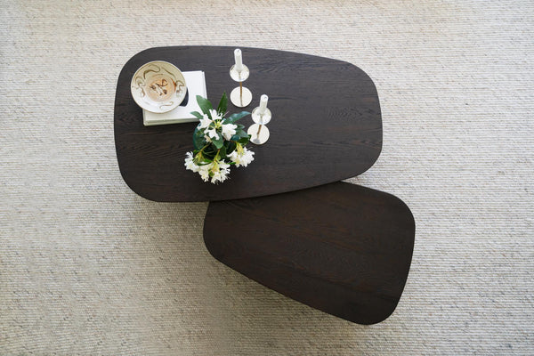 Soffbord i mörkt trä med organisk form, två nivåer, dekorerat med vita blommor och ljusstakar