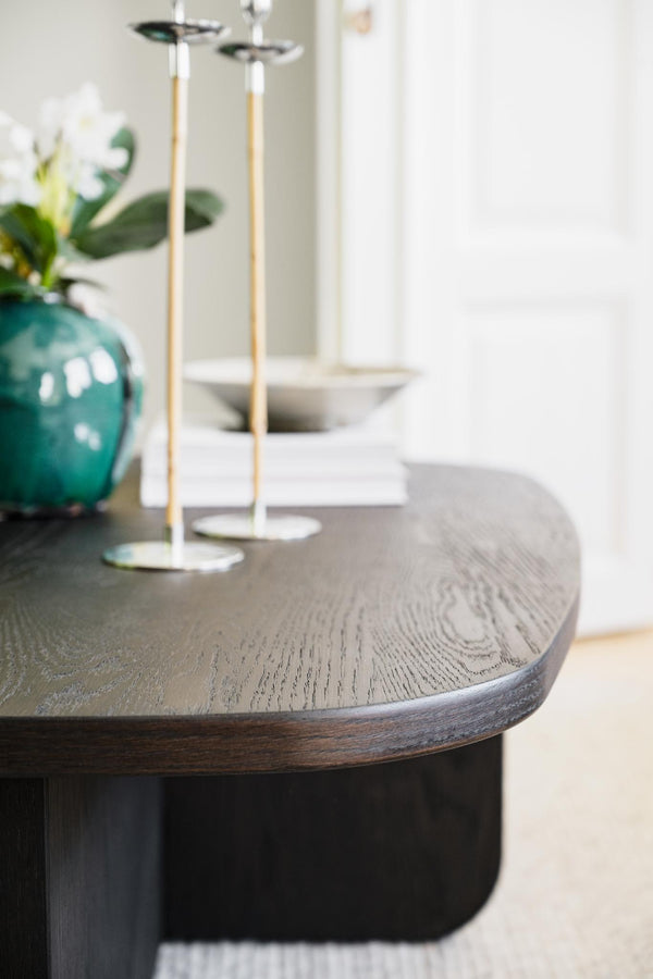 Runt matbord i mörk ek med ljusgråbetsad träskiva, dekorerat med turkos vas och vita ljusstakar