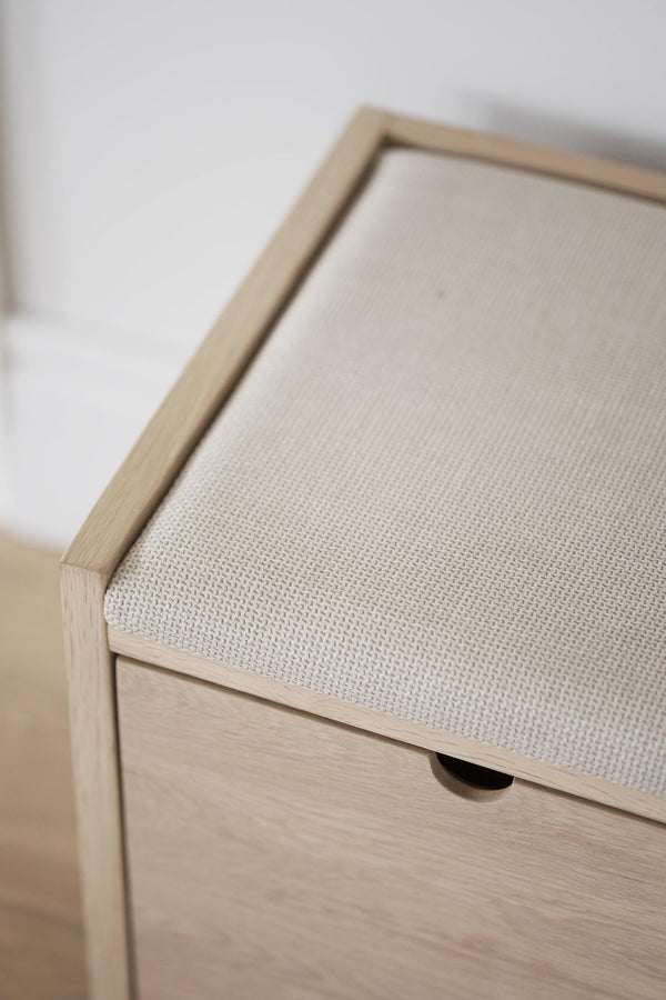 Hallbänk med stoppad sits i beige tyg och ljust trä med låda