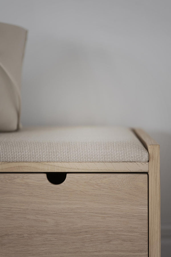 Sittbänk i ljust trä med stoppad sits i beige tyg och förvaringslåda under