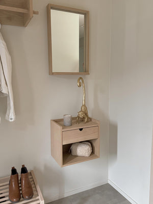Väggmonterad hallmöbel i ljust trä med spegel, låda och öppen hylla med handduk i minimalistisk entré