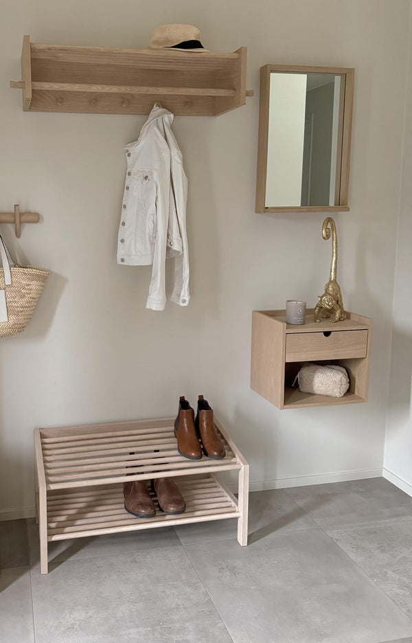 Minimalistisk hall med skoställ i trä, väggmonterad spegel, hylla med klädhängare och förvaringslåda