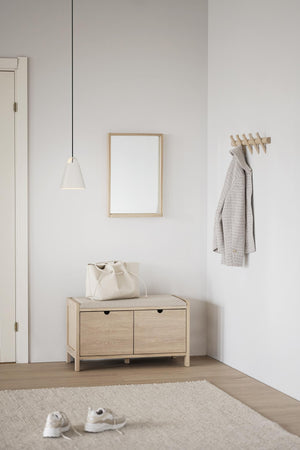 Minimalistisk hall med hallmöbel i ljust trä, spegel, klädhängare och vit pendel-lampa