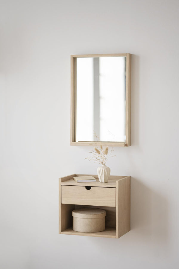 Väggmonterad sängbord i ljust trä med spegel, låda och öppen hylla med dekoration