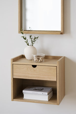 Sängbord i ekfanér med låda och öppen hylla, monterat på vägg under spegel med dekorativa detaljer