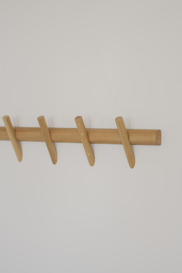 Knaggrekke i lyst tre med fire knagg-pinner montert på hvit vegg
