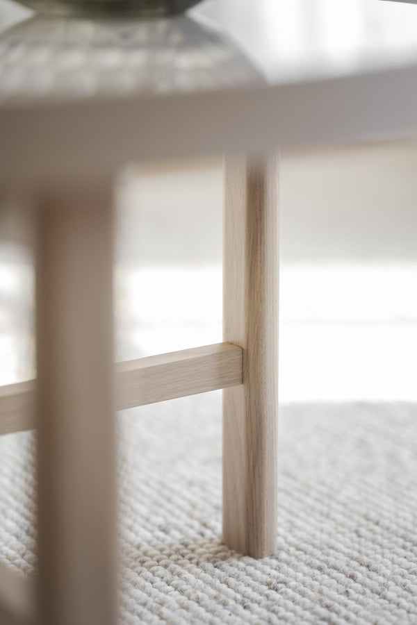 Närbild på ljusa träben hos pall eller stol på ljus vävd matta i naturmaterial