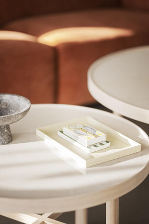 Matchbox och dekorativa brickor på runt vitt soffbord med stenbägare i bakgrunden