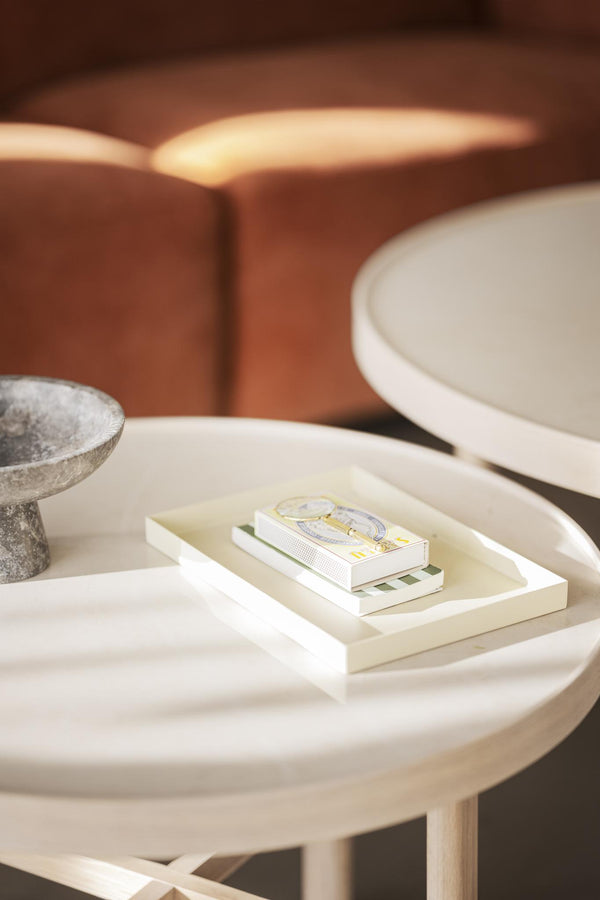 Matchbox och dekorativa brickor på runt vitt soffbord med stenbägare i bakgrunden