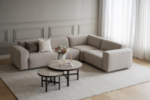 Beige modulsoffa i hörnutförande med runda soffbord och ljus matta i elegant vardagsrum