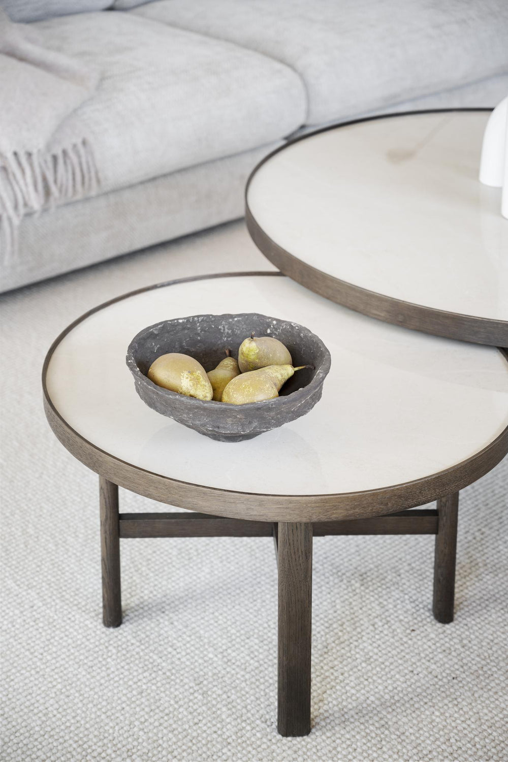 Runt soffbord i mörkt trä med ljus skiva och kryss-underrede i modern skandinavisk design