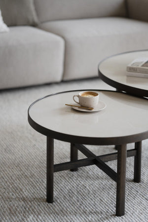 Runt soffbord med vit marmorskiva och svarta träben, kaffekopp med fat på bordet i moderna vardagsrum