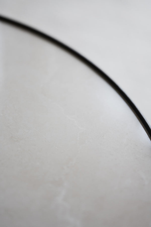 Närbild av svart böjd linje mot vit bakgrund, minimalistisk och grafisk detalj