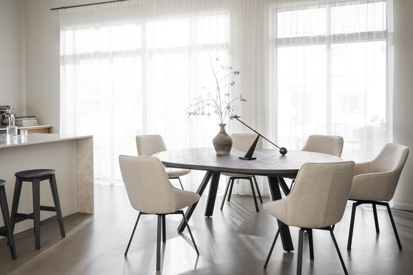 Matbord med sex beige stolar i modern matsal med stora fönster och ljust interiör