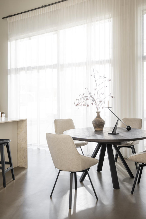 Rund matbord i mörk ek med beige stoppade stolar i modern matsal med vita gardiner och naturligt ljus