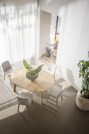 Runt matbord i ljust trä med fyra stoppade stolar i beige tyg, skandinavisk design med minimalistisk inredning