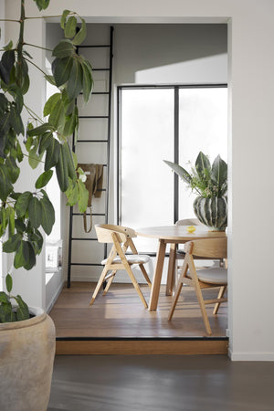 Matplats med runt matbord i ljust trä och matchande stolar i skandinavisk design med gröna växter