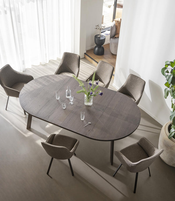 Ovalt matbord i grå keramik med sex grå stolar runt bordet i modern matsal med vita väggar