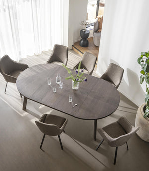 Oval matbord i grått med sex stolar runt, sett ovanifrån i ljust matrum med vita gardiner