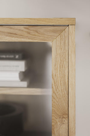 Närbildsdetalj av ljust ekfanerat hörn på spegel eller skåp med synlig trästruktur och snickerikvalitet