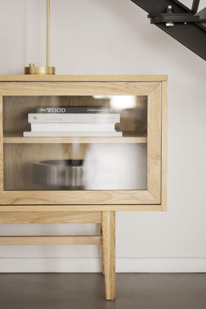 Sängbord i ek med glasdörr och synlig bokhylla, moderna träben och minimalistisk design