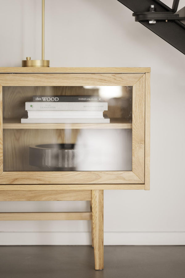 Sängbord i ek med glasdörr och synlig bokhylla, moderna träben och minimalistisk design