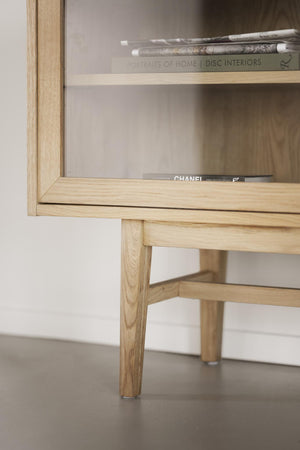 Sängbord i ljus ek med öppen hylla, designade ben och böcker på hyllplanet