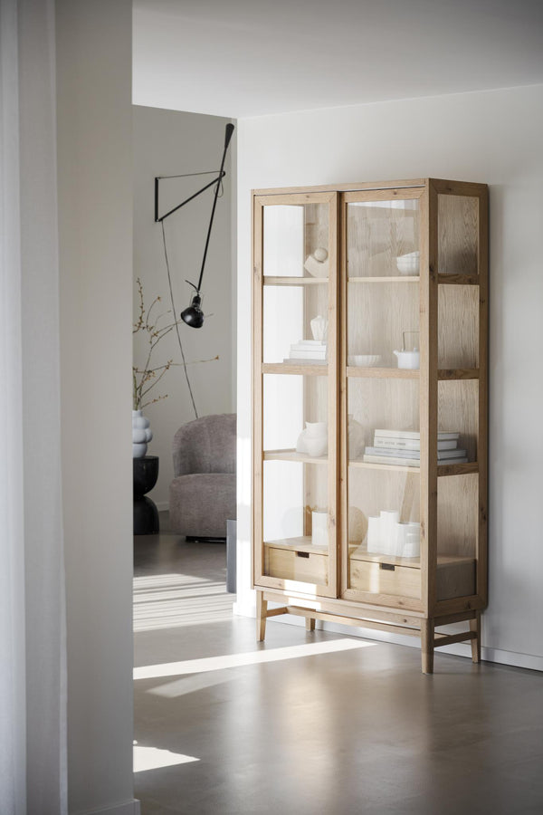 Vitrinskåp i ljust trä med glaspaneler, fyra hyllplan och två lådor, skandinavisk design i minimalistiskt hem