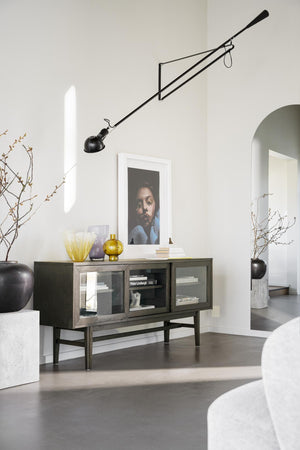 Skänk med glasdörrar i mörkt trä med dekorativa vaser och konst i ljust vardagsrum med designlampa