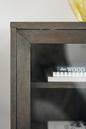 Närbildsdetalj av möbelhörn i mörkt trä med glaspanel och synlig trästruktur