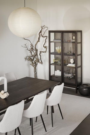 Modern matplats med mörkt träbord, vita stolar, rund rislampa och vitrinskåp med glasdörrar