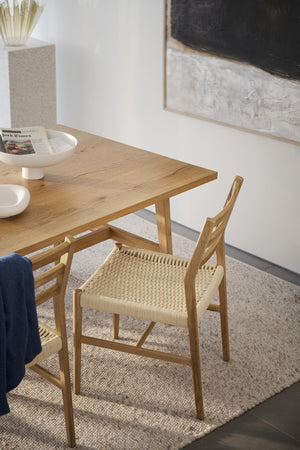 Matsalsstol i ek med flätad sits vid matbord av massiv ek på ljus matta i skandinavisk inredning