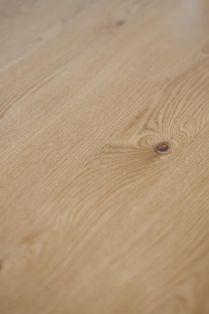 Ljust trägolv i ek med naturlig trästruktur och synlig kvist i närbild