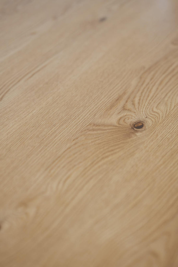 Ljust trägolv i ek med naturlig trästruktur och synlig kvist i närbild