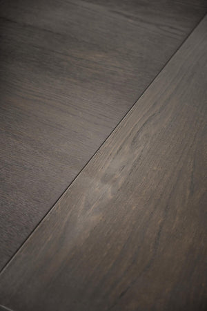 Närbild på mörkgrå laminatgolv med trästruktur och synlig fog mellan plankorna