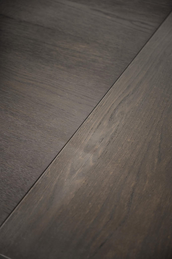 Närbild på mörkgrå laminatgolv med trästruktur och synlig fog mellan plankorna