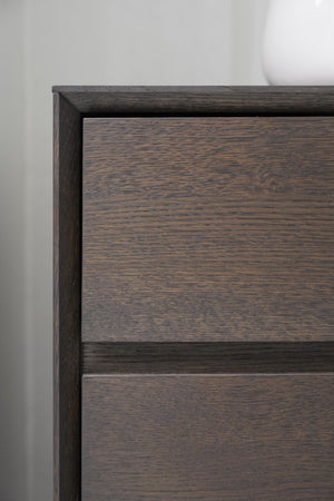 Närbilds detalj av mörkbrun byrå med synlig trästruktur och två lådor i modern design