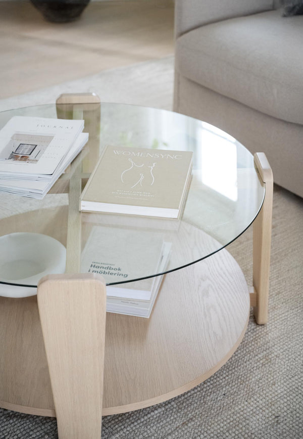 Runt soffbord i ljust trä med glasskiva och böcker, skandinavisk design för vardagsrum