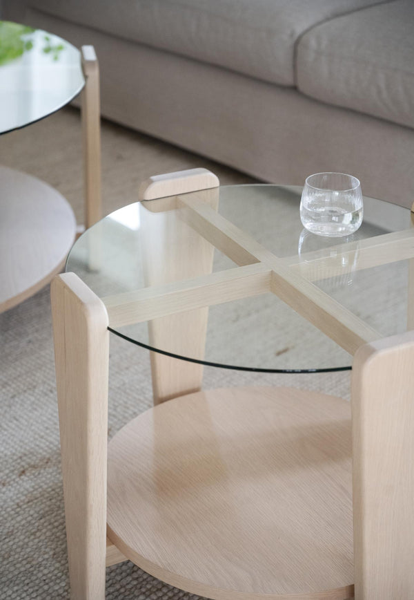 Soffbord i ljust trä med glasskiva, rund hylla och minimalistisk design i skandinavisk stil