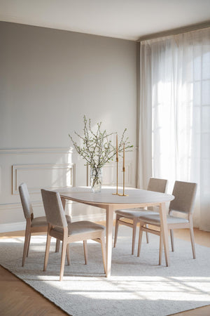 Ljus matgrupp i trä med fyra stoppade stolar, runt bord och minimalistisk skandinavisk design