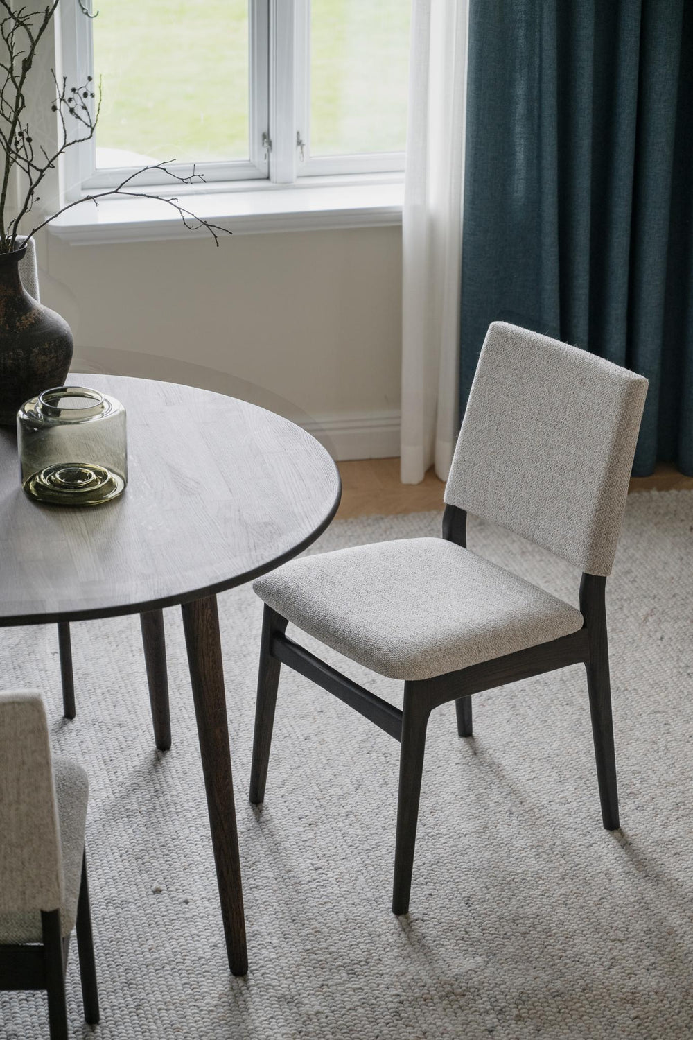 Ljusgrå stoppad matstol med mörkbruna träben i modern skandinavisk design