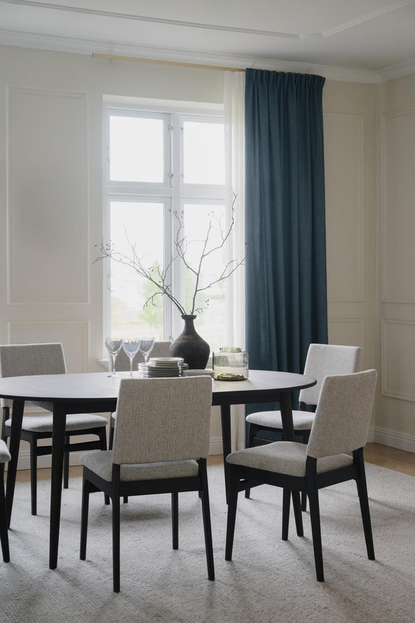 Matgrupp med ovalt bord i svart trä och fyra stoppade stolar i ljusgrått tyg, minimalistisk skandinavisk design