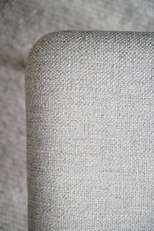 Närbild av ljusgrå möbel med tygklädsel i strukturerad vävd textil mot neutral bakgrund