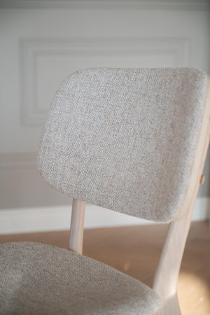 Närbild på stoppad ryggdyna i ljusgrå melerad klädsel på stol med trästomme