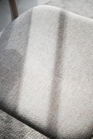 Närbild på stoppad stolsdyna i ljusgrå och beige melerad klädsel med mjuk textilstruktur