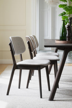 Gråa stoppade matstolar med mörkbruna träben vid matbord i modern matsal