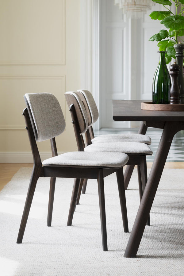 Gråa stoppade matstolar med mörkbruna träben vid matbord i modern matsal