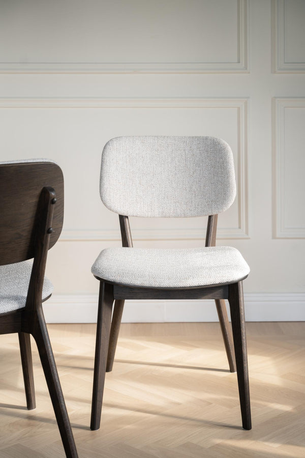 Matstol med grå klädsel och mörka träben i modern skandinavisk design