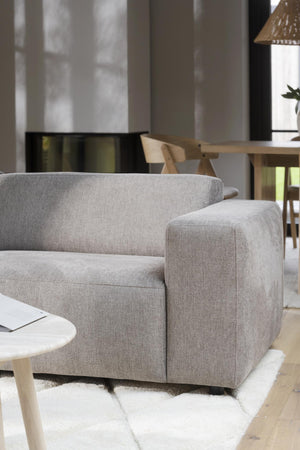 Grå soffa med träbord och stol i modern skandinavisk vardagsrumsinredning