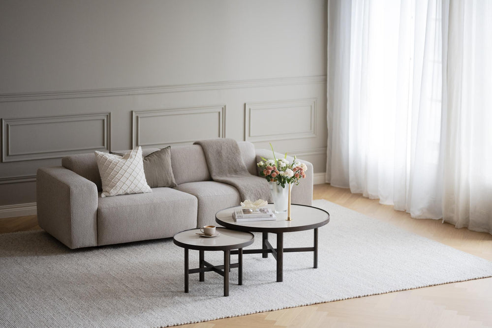 Beige tvåsitsssoffa med blockformade armstöd och låga träben i modern skandinavisk design